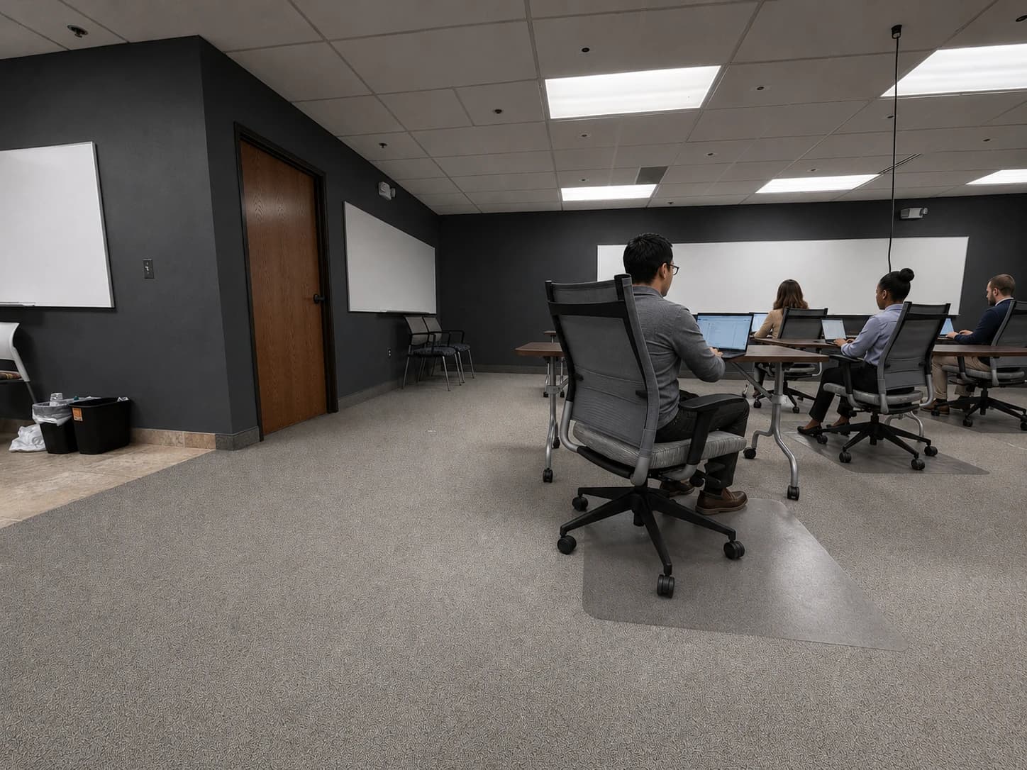 Students working at laptops along the back row of the training room